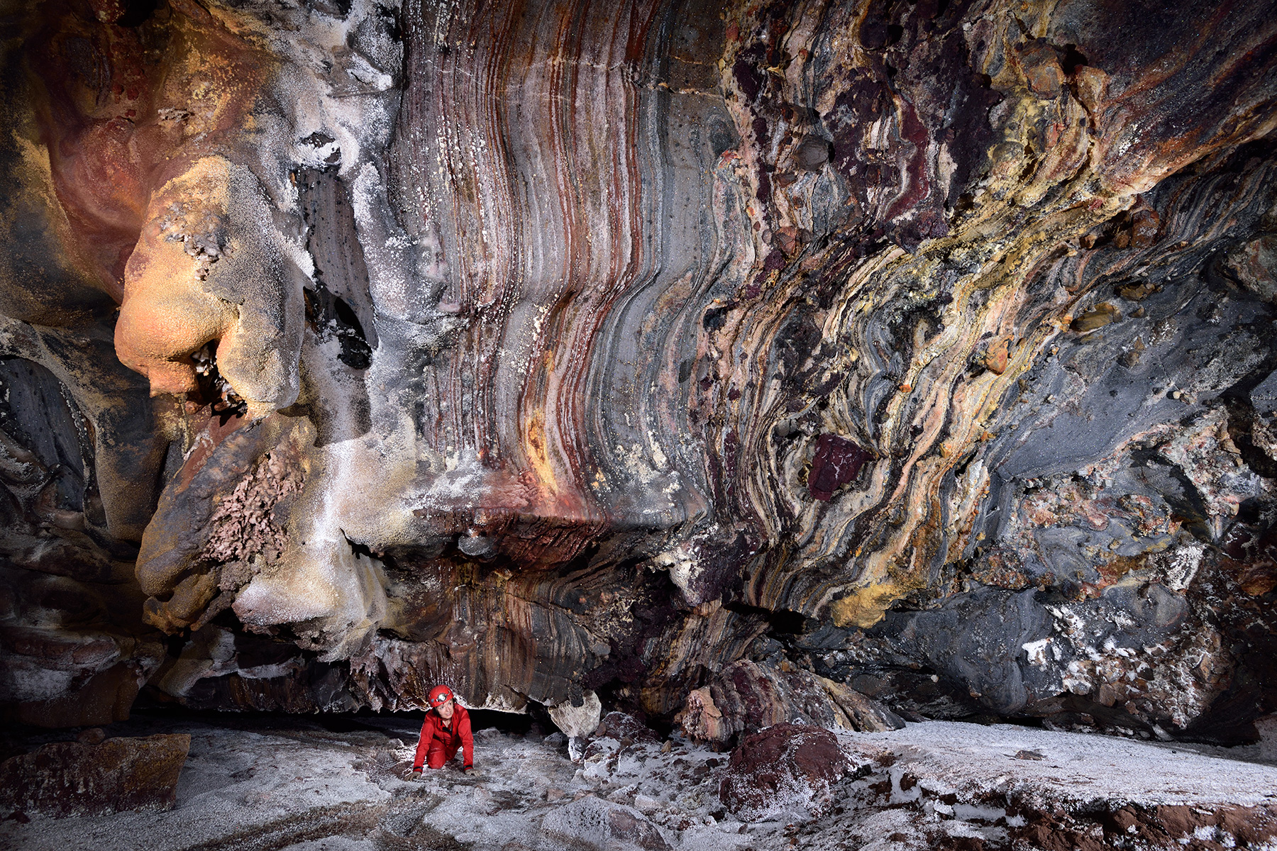 Daneshjoo Cave (Iran, île d'Hormoz) : spéléo débouchant d'un passage bas dans une salle avec dépôts de sel colorés