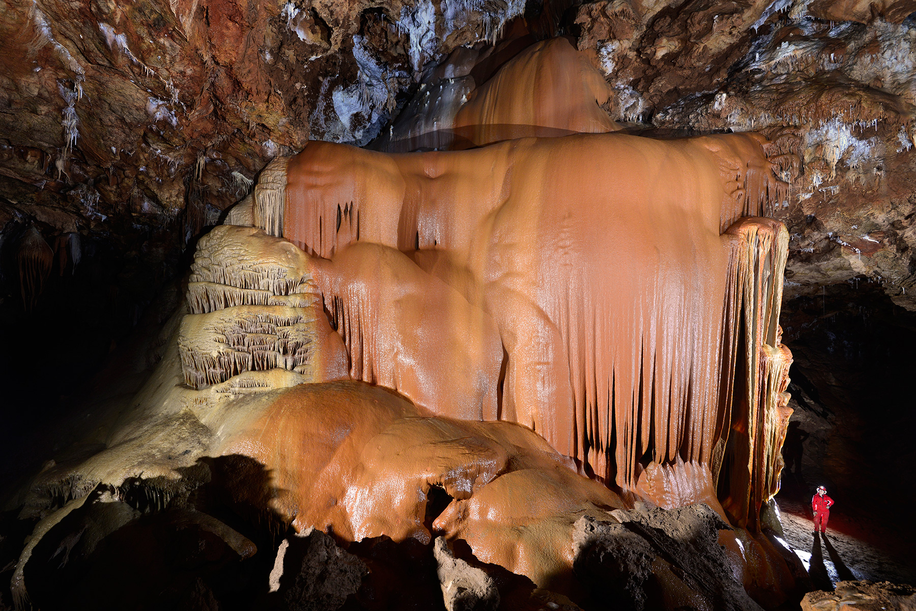 Grotte de Clamouse - Le "Niagara rouge" de face : grande coulée de calcite colorée (rouge et jaune) avec spéléo au pied