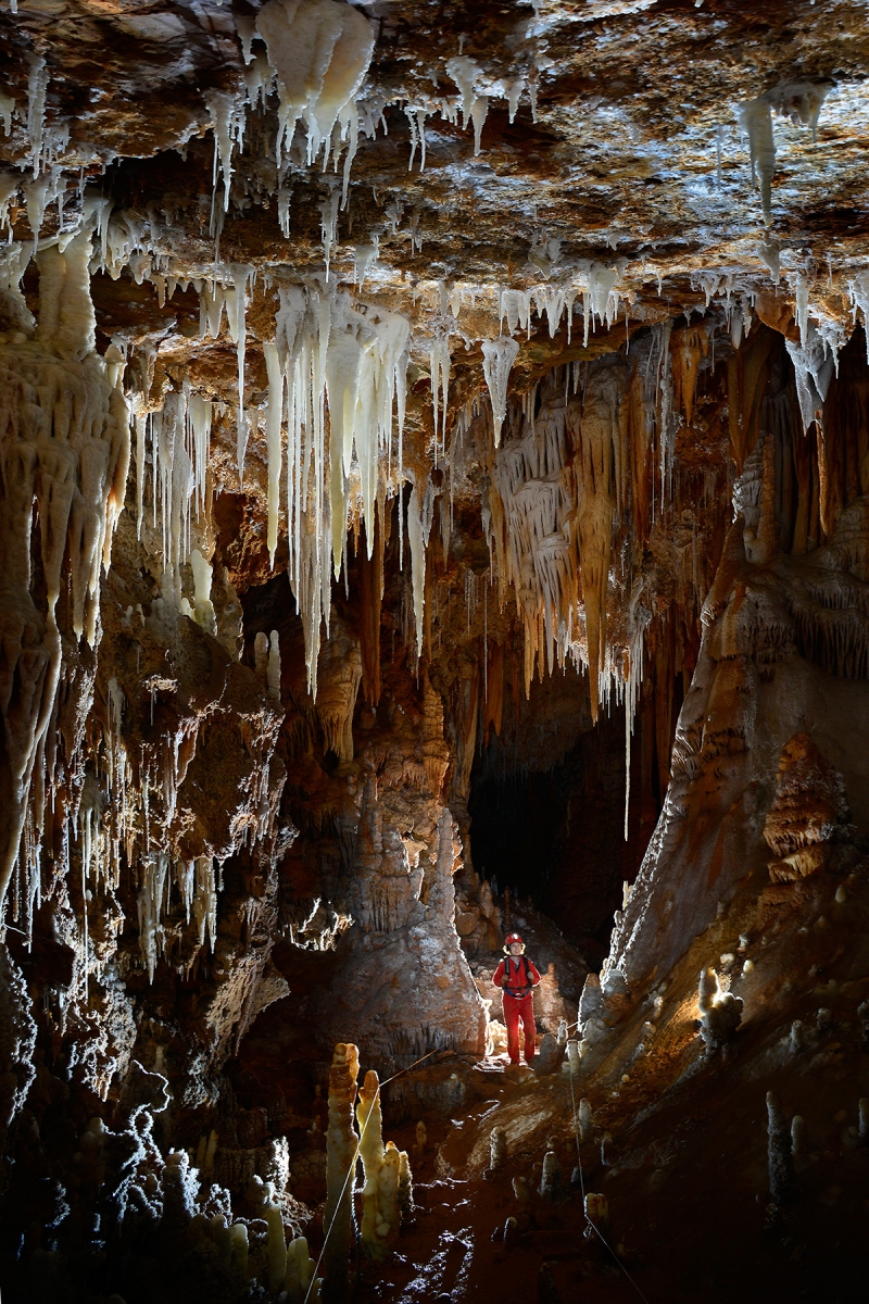 Grotte de Clamouse - Spéléo progressant dans une grande galerie concrétionnée (stalactites, stalagmites, coulées, ....).