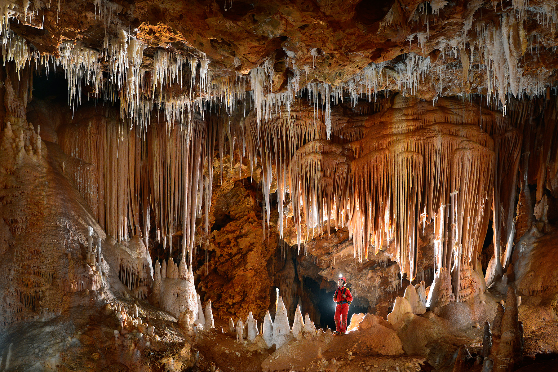 Grotte de Clamouse - Fenêtre dans un ensemble de piliers, stalagmites et stalactites massives (la mâchoire) avec spéléo au centre.