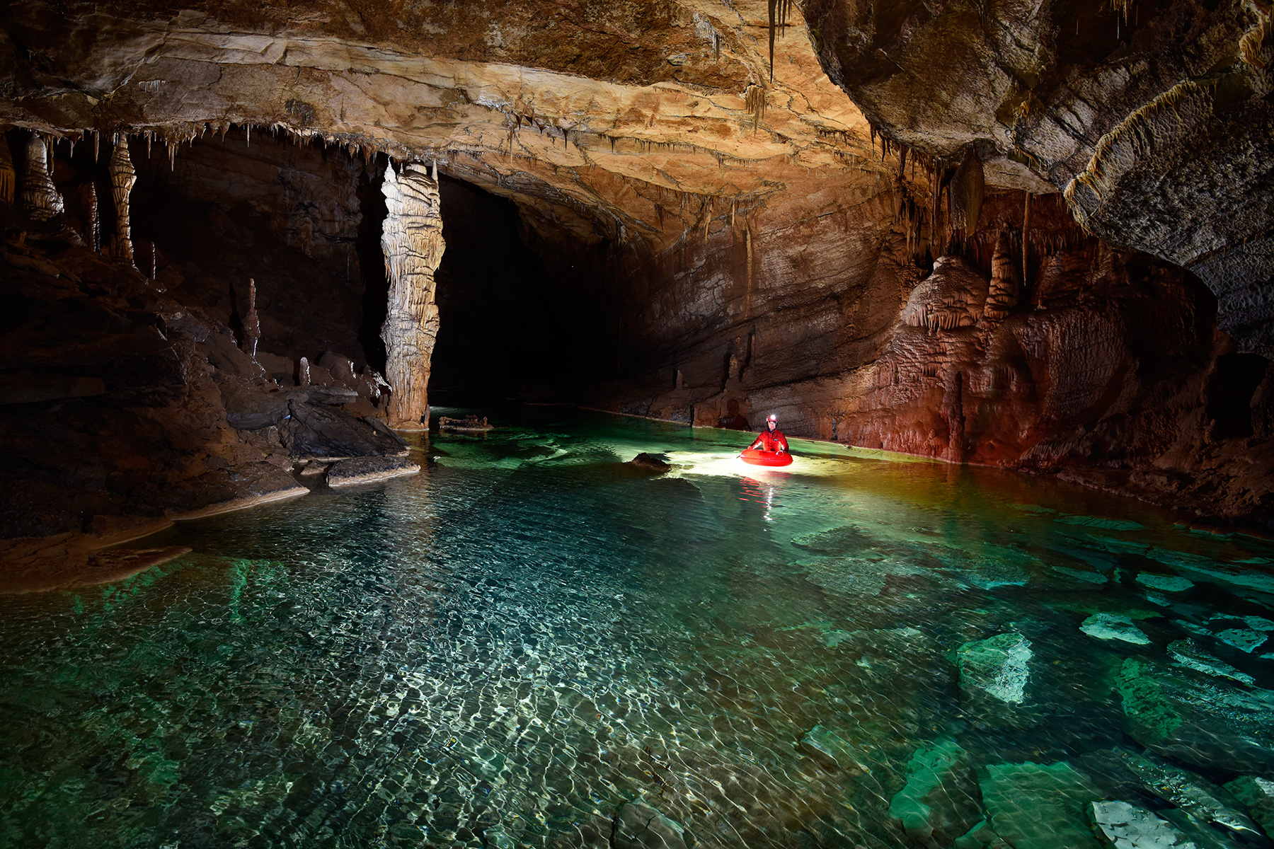 Krizna Jama (Slovénie) - Spéléo progressant en canot dans une rivière souterraine aux eaux vertes (grand pilier blanc)