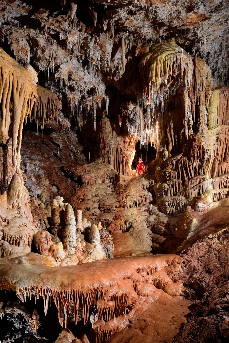 Grotte de Clamouse (partie aménagée) - Spéléo en haut de grandes coulées de calcite avec colonnes, stalactites et stalagmites (plancher stalagmitique en premier plan)