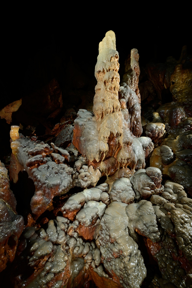 Grotte de Dargilan partie touristique (Lozère) - Stalagmite reposant sur des dépôts de calcite colorée (grande salle du Chaos)