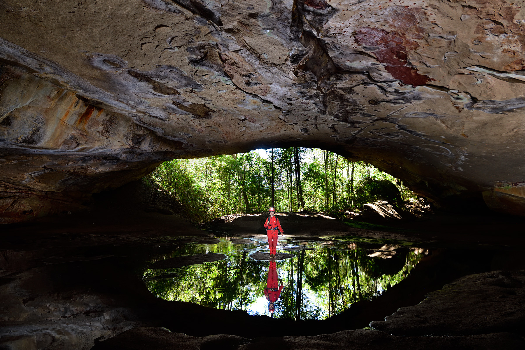 Gruta Aroe Eiari (Mato Grosso, Brésil) - Entrée se reflétant dans l'eau avec personnage au centre.
