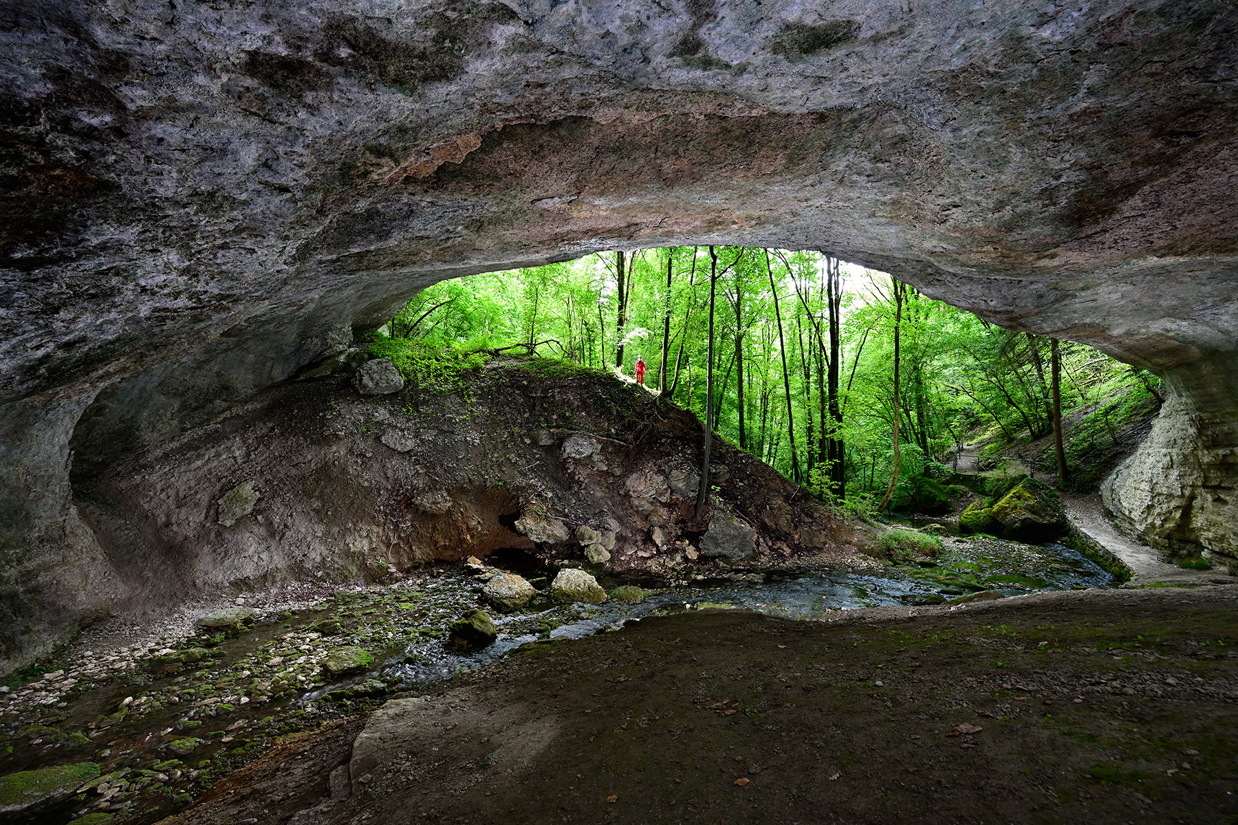 Grotte de Plaisir Fontaine (Doubs) - Porche d'entrée avec personnage vu de l'intérieur