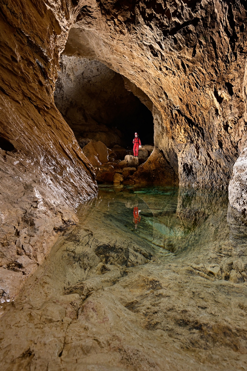 Grotte de Bournillon (Isère) - Marmite remplie d'eau près de l'entrée avec spéléo sur un rocher en arrière plan