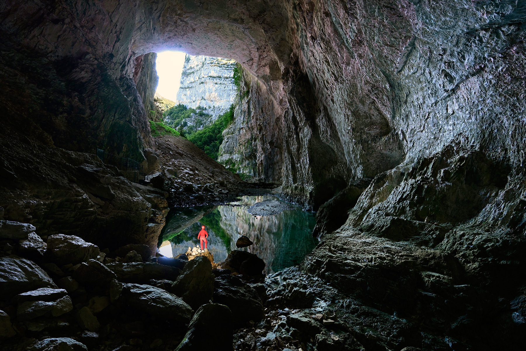 Grotte de Bournillon (Isère) - Porche d'entrée avec reflet dans le lac (horizontale - spéléo en premier plan)