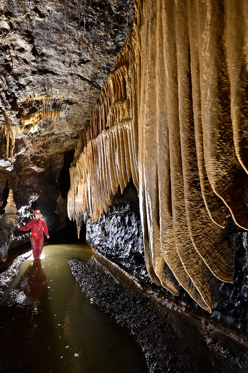Grotte du Crotot (Doubs) - Galerie avec rivière et grandes draperies (spéléo en fond)