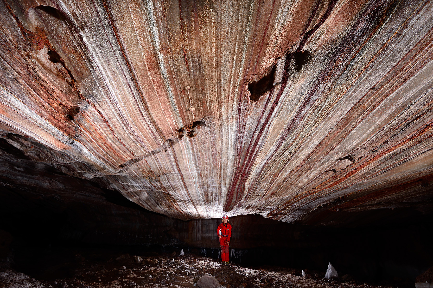 3N Cave (Iran, île de Qeshm, diapir de sel de Namakdan) - Entrée supérieure :  spéléo dans une galerie avec des couches de sel colorées au plafond (blanc, rose, orangé, rouge)