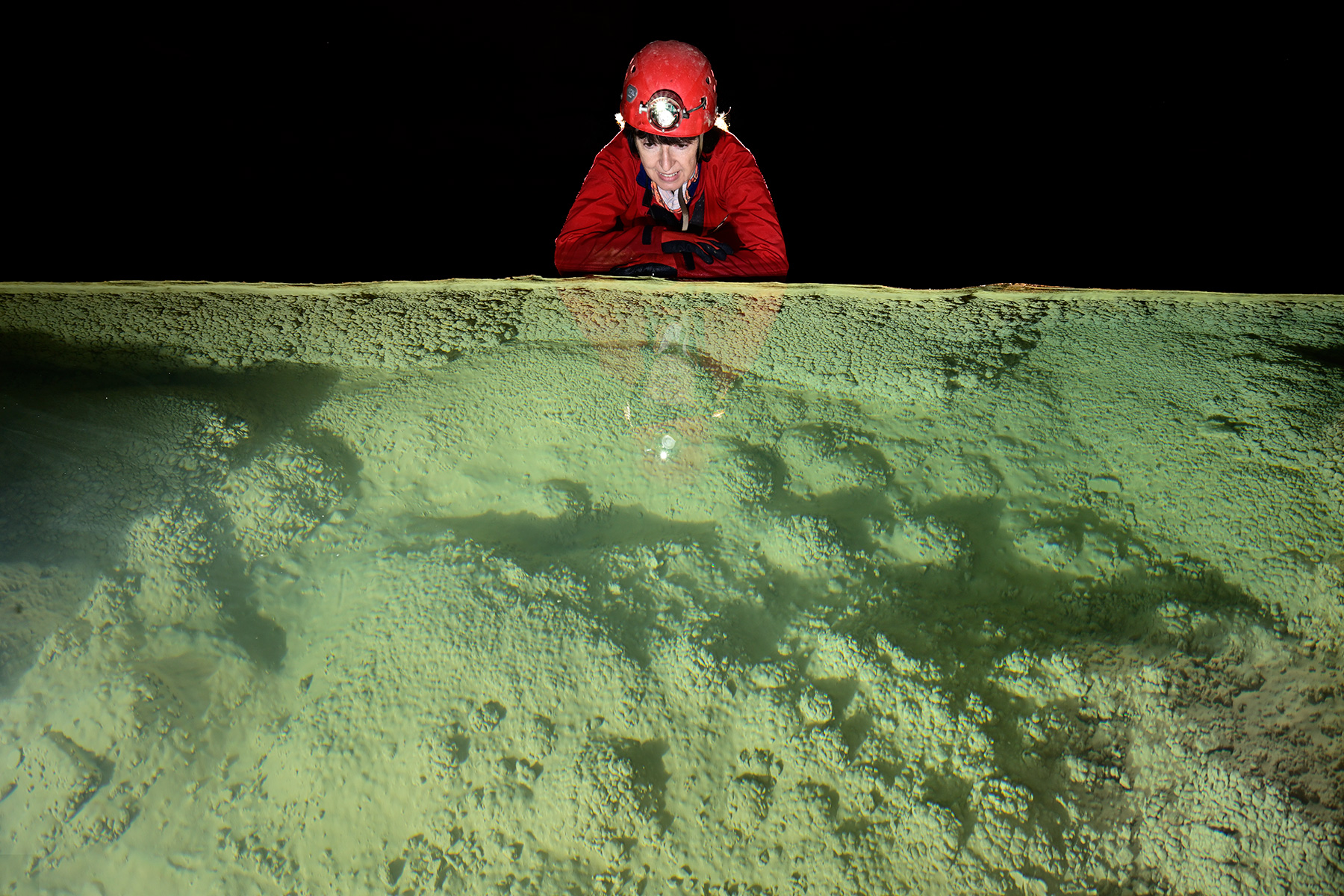 Grotte de Trabuc (Gard) - Spéléo regardant des cristallisations dans un gour avec eau verte
