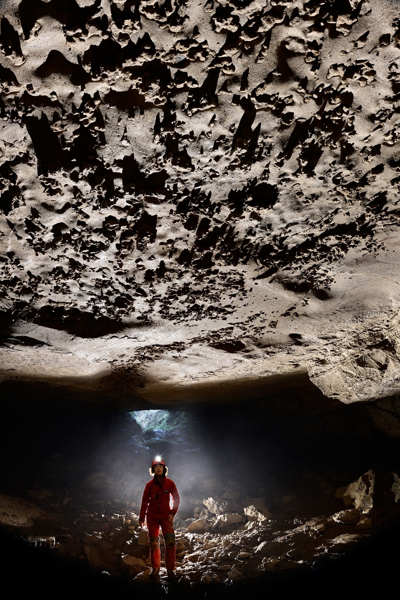 McClung Cave (Virginie occidentale, USA) - Spéléo regardant un plafond avec des incrustations (entrée en arrière plan)