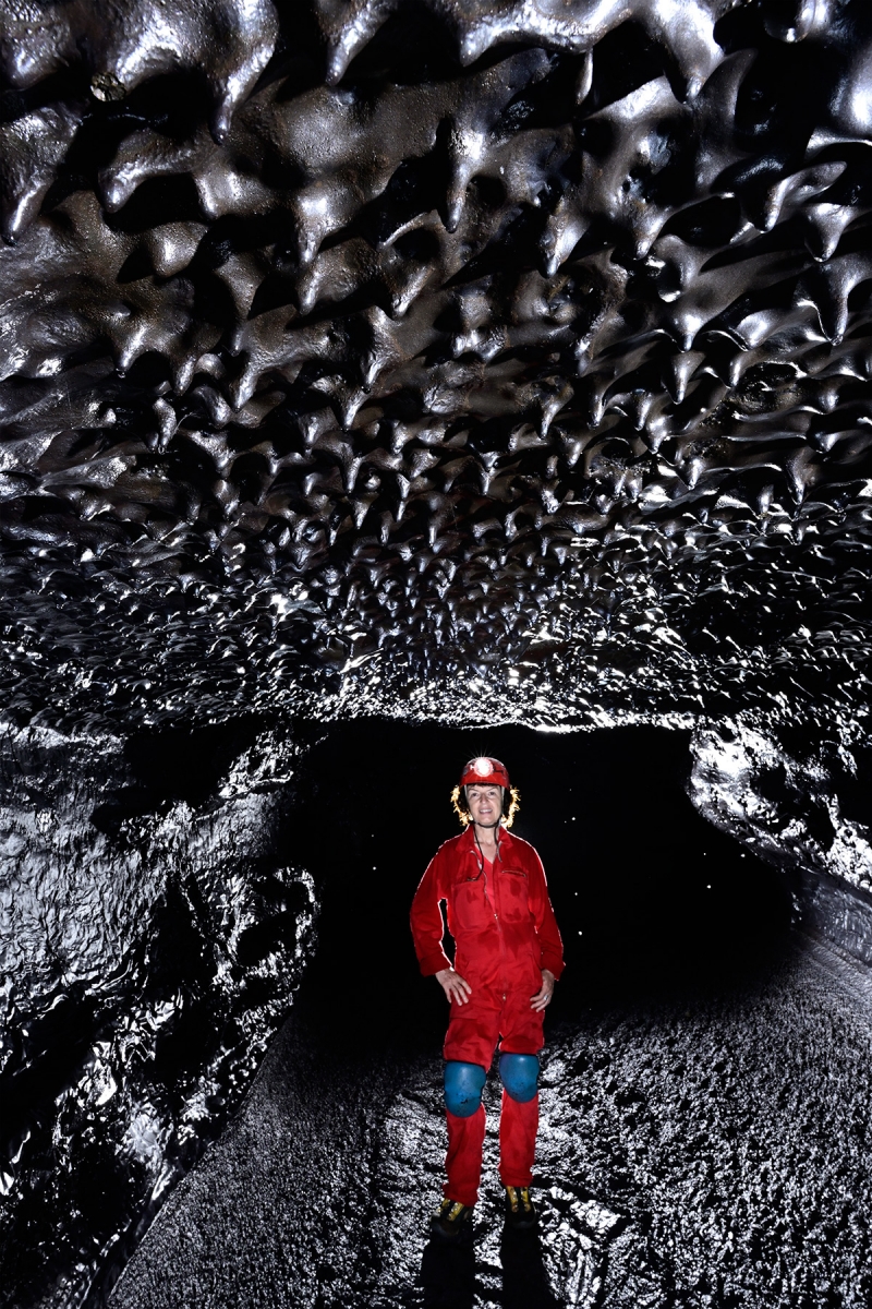 Tunnel de lave de la coulée 2004 (La Réunion) - Spéléo regardant des petites stalactites au plafond ("chocolate drops") 