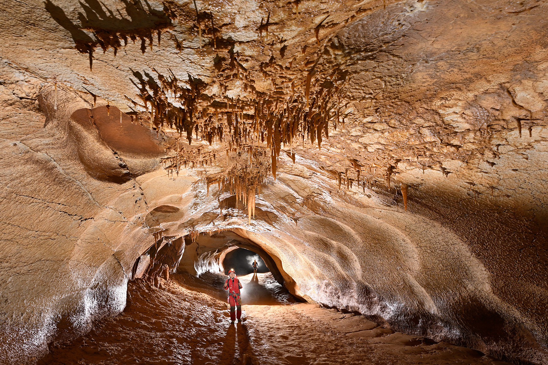 Traversée Aven Despeysse - Grotte de Saint-Marcel (Ardèche) - Deux spéléos dans une galerie avec stalactites au plafond