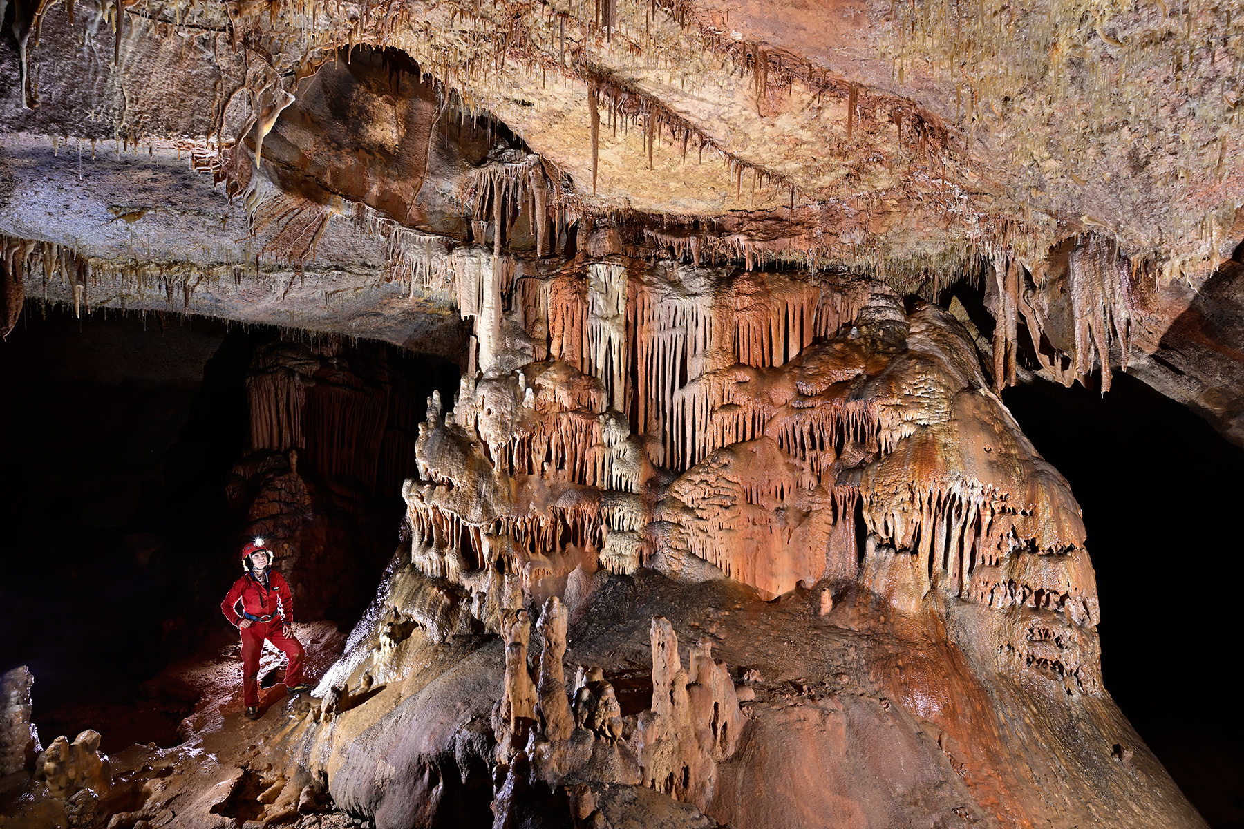 Grotte de Saint-Marcel d'Ardèche (réseau I) - Spéléo à côté d'une gros pilier avec de coulées colorées