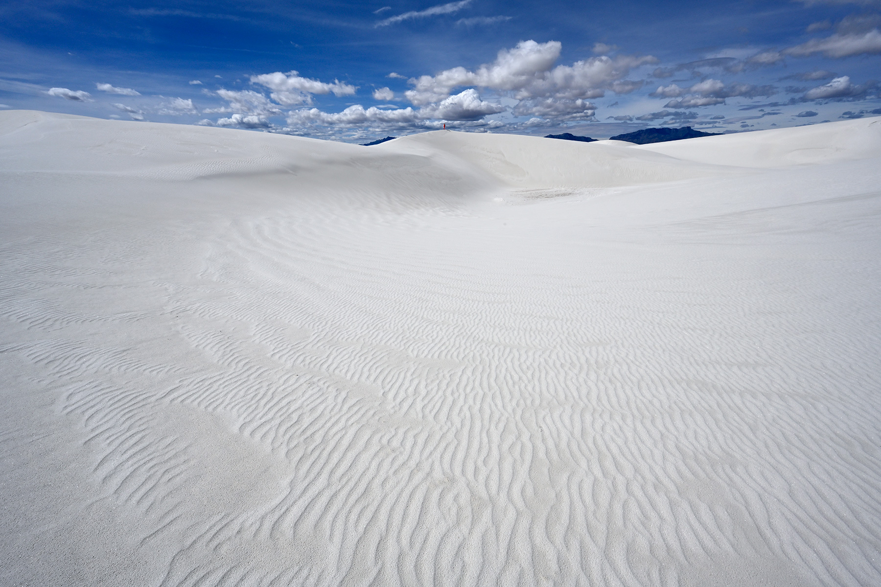 White Sands National Park (Nouveau Mexique, USA) - Grande dune de sable blanc avec rides en premier plan et personnage lointain en rouge au sommet