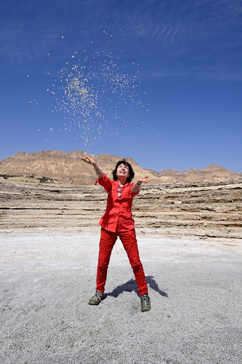 Mer Morte (Israël) - Femme jetant une poignée de perles de sel sur le rivage de la Mer Morte