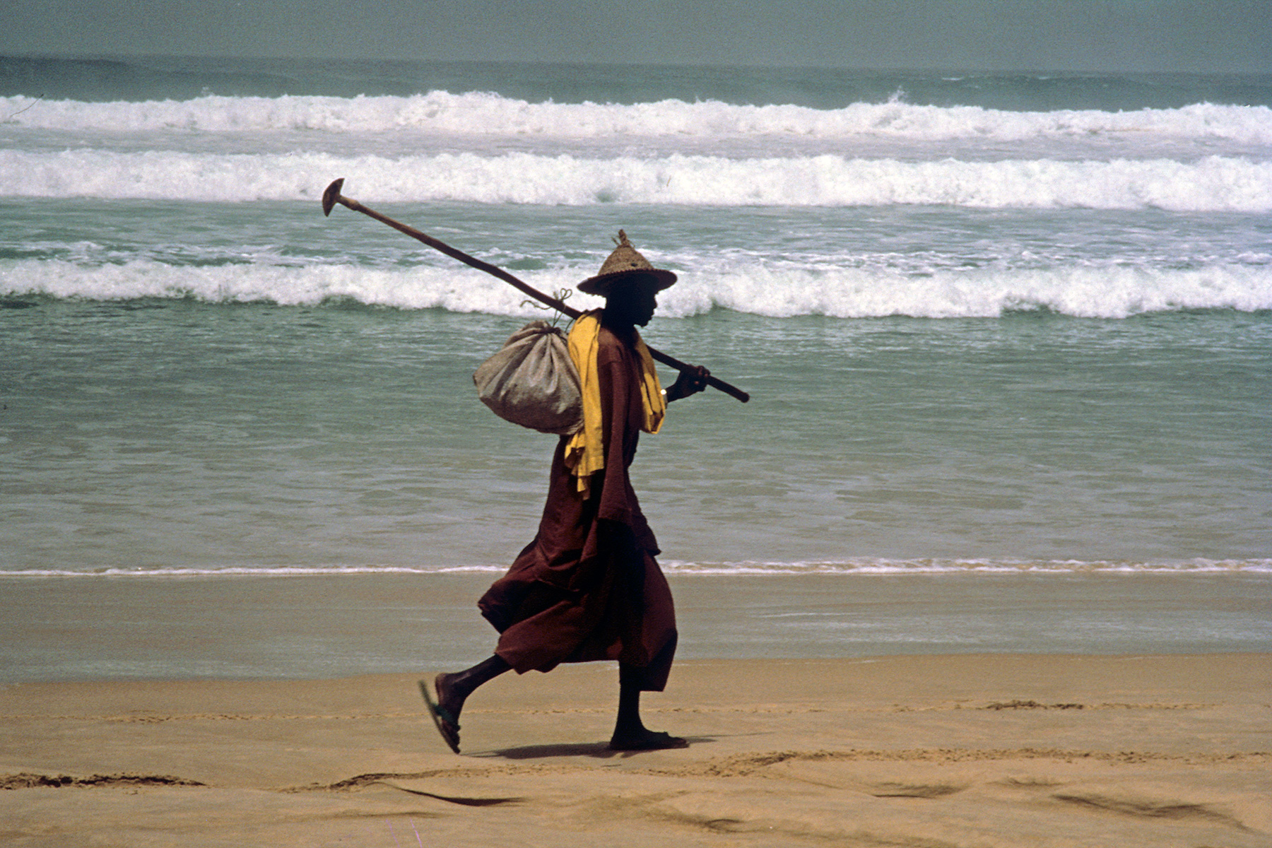 Sénégal - Homme marchant au bord de l'océan (avec chapeau traditionnel)