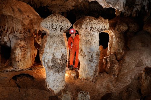 Cueva de Santa Catalina (Expédition Cuba 2012 - Team La Salle). Spéléo debout derrière deux hautes concrétions en forme de champignons.(SP-12-0045)
