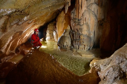 Grotte de Saint-Marcel (Ardèche) - Spéléo accroupie au bord d'un petit gour(SP-12-1008)