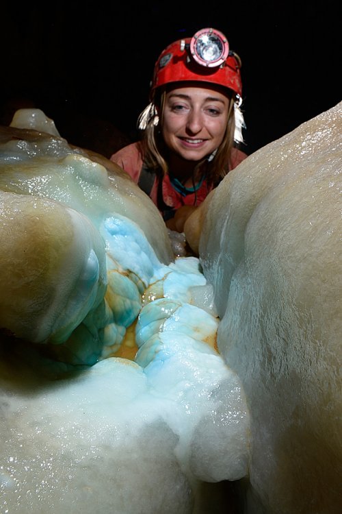 Grotte des Ecossaises - Dépôt d'aragonite bleue sur une coulée de calcite (avec jeune femme spéléo en arrière plan)(SP-15-0652)