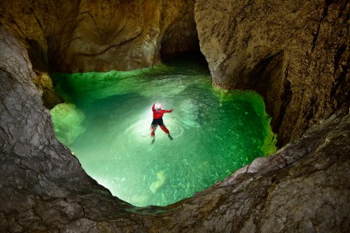 Novokrajska Jama (Slovénie) - Spéléo traversant à la nage une grande vasque d'eau verte(SP-17-0472)