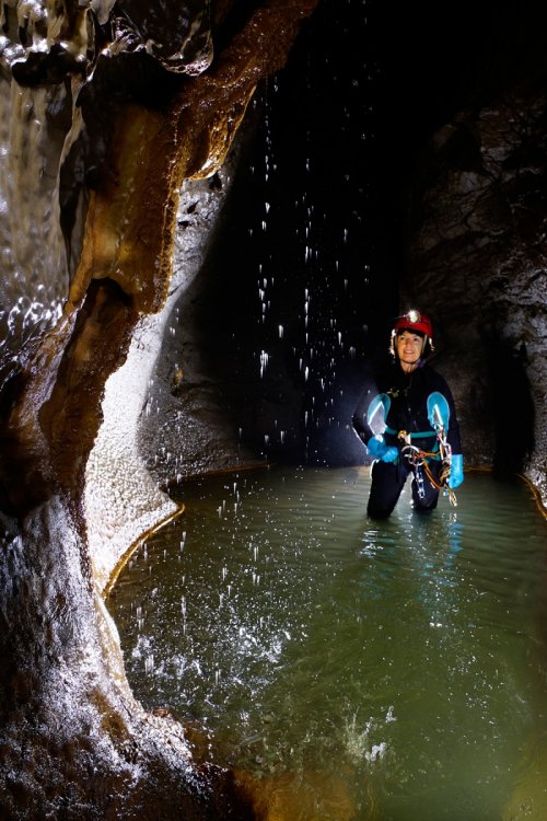 Markov Spodmol (Slovénie) - Cascatelle en contre jour dans une rivière souterraine avec spéléo en arrière plan(SP-17-0405)