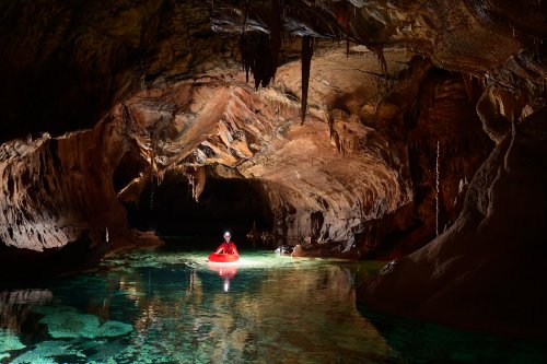 Krizna Jama (Slovénie) - Spéléo progressant en canot dans une rivière souterraine eaux vertes(SP-17-0414)
