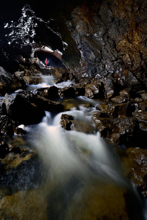 Otoska Jama (Slovénie) - Rivière souterraine (la Pivka) s'écoulant sur des blocs avec spéléo en arrière plan (SP-17-0448)