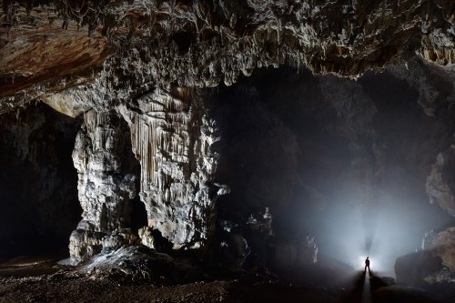 Dimnice Jama (Slovénie) - Gros piliers dans une salle envahie par le brouillard avec spéléo sur le côté en contre-jour(SP-17-0494)