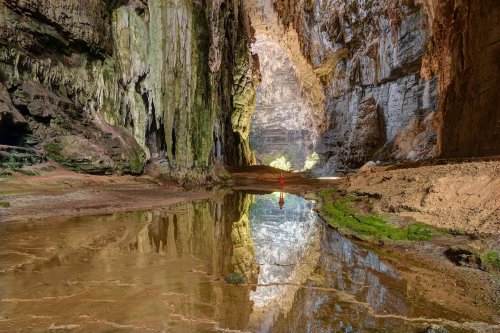 Lapa do Janelao (Itacarambi, Minas Gerais) - Grande galerie éclairée la lumière du jour avec spéléo en fond (reflet dans l'eau)(SP-16-0473)