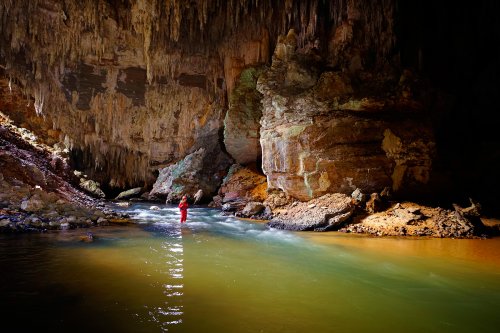 Lapa do Sao Bernardo (Sao Domingos, Goiás) - Spéléo progressant dans rivière éclairée par la lumière du jour à l'entrée de la cavité.(SP-16-0572)