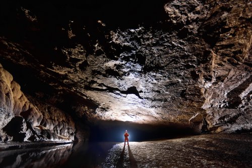 Lapa Sao Matheus II (Sao Domingos, Goiás) - Spéléo contre-jour dans large galerie au sol plat avec rivière.(SP-16-0624)