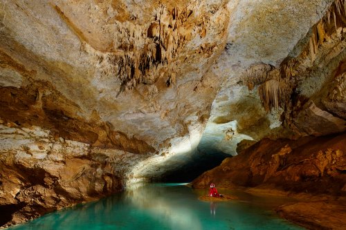 Lapa do Convento (Lage dos Negros, Bahia) - Rivière d'eau bleue avec personnage sur une petite île. Cette rivière est couverte de calcite flottante.(SP-16-1100)