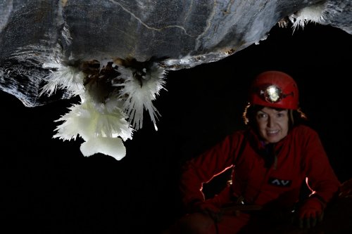 Grotte de Roquebleue (Hérault) - Spéléo regardant une aragonite sur les calcaires rubanés bleus(SP-19-0035)