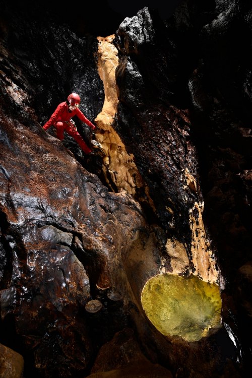 Grotte de Vallorbe (Suisse) - Spéléo désescaladant une petite cascade à sec avec des dépôts de calcite jaune et une vasque d'eau à sa base(SP-19-0079.jpg)
