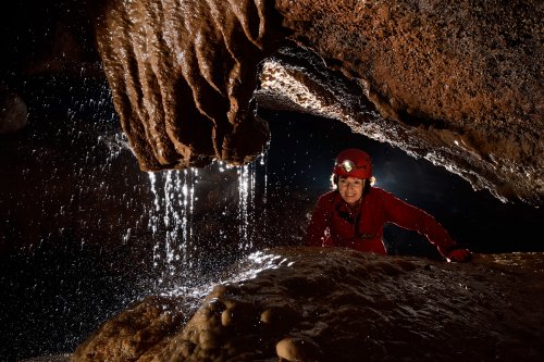 Seyryu-Kutsu (Blue Dragon Cave) (Hirao-dai, Fukuoka, Japon) - Fontaine sortant d'une grosse stalactite coupée avec spéléo en arrière plan(SP-19-0302)