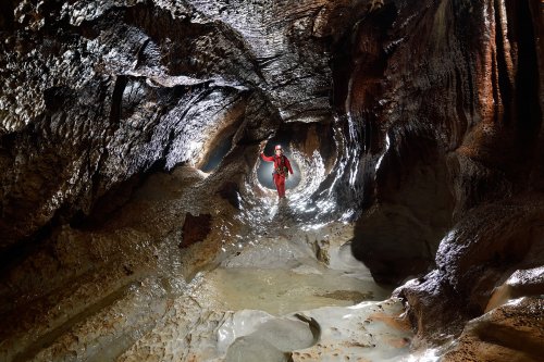 Event de Peyrejal (Ardèche) - Spéléo dans galerie avec pilier central et petites vasque d'eau claire en premier plan(SP-20-0123)