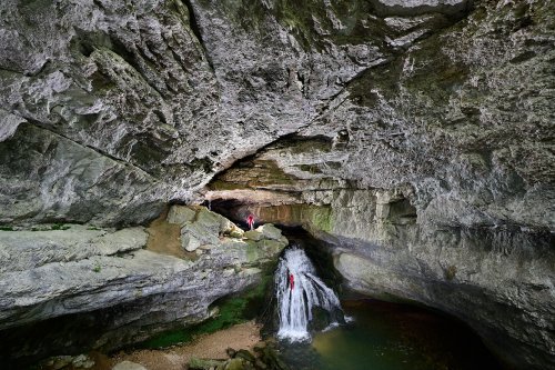 Source du Pontet (Doubs) - Porche d'entrée avec un spéléo descendant la cascade et un autre perché en haut de celle-ci (vue d'ensemble)(SP-20-0332)