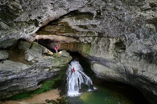 Source du Pontet (Doubs) - Porche d'entrée avec un spéléo descendant la cascade et un autre perché en haut de celle-ci (vue rapprochée)(SP-20-0330)