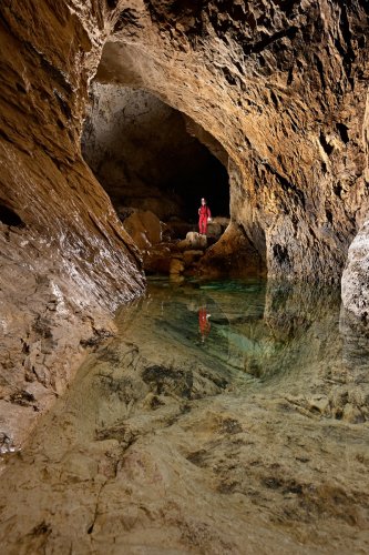 Grotte de Bournillon (Isère) - Marmite remplie d'eau près de l'entrée avec spéléo sur un rocher en arrière plan(SP-20-1276)