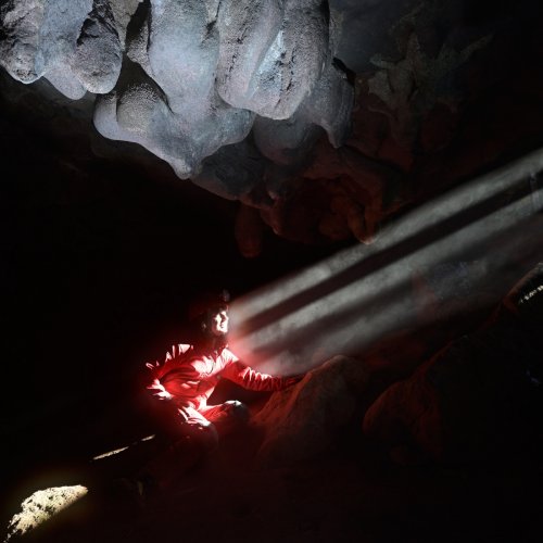 Rapps Cave (Virginie occidentale, USA) - Spéléo éclairé par des rayons de soleil passant à travers la grille d'entrée(SP-21-2120)