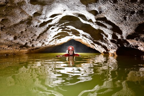 Grotte du moulin de Vermondans (Doubs) - Progression en nageant dans la rivière au niveau d'une voûte mouillante (fort contre-jour)(SP-22-1450)
