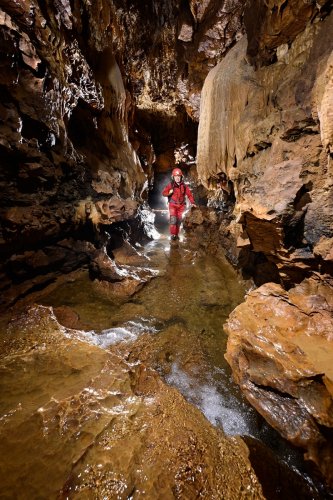 Grotte de Foissac (Aveyron) - Progression dans la rivière souterraine entre des coulées de calcite(SP-23-0637)