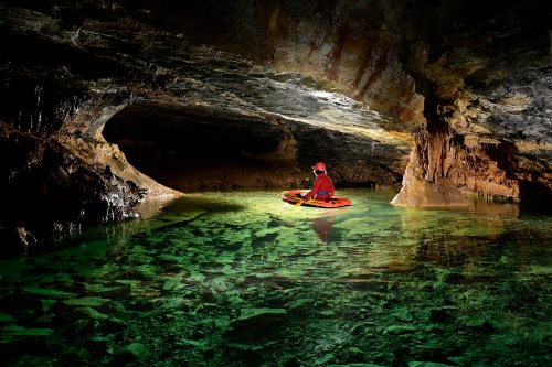 Grotte de la Cabane de Saint-Paul des Fonts (Aveyron) - Spéléo traversant en canot un petit lac (personnage éclairé)(SP-23-1550)