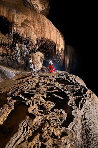 Grotte de Tham Nam Hoo (province de Mae Hong Son, Thaïlande) - Spéléo devant un ensemble de petits gours suspendus au dessus de la rivière (vue ensemble avec coulées orange en fond)(SP-24-0535)