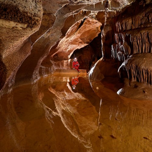 Grotte de Saint-Marcel d'Ardèche (réseau I) - Gour avec spéléo assis dans le fond sur la barrière (reflet dans l'eau) - Format carré(SP-24-2459)
