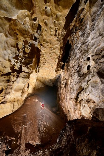 Grotte de Saint-Marcel d'Ardèche (Galerie du lac) - Spéléo progressant sue une dune de dépôts argileux rouges dans une grande galerie verticale  (SP-24-2533)