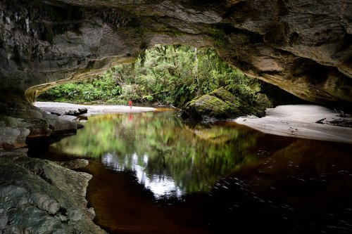 Karamea (Nouvelle-Zélande, Ile du sud) - Moria Gate Arch dans Oparara Basin : vue de l'intérieur (avec personnage en fond)(VO-24-1393)
