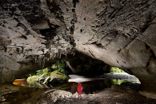 Karamea (Nouvelle-Zélande, Ile du sud) - Moria Gate Arch dans Oparara Basin vue de l'intérieur (avec personnage)(VO-24-1374)
