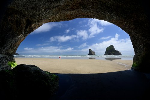 Plage de Wharakiki (Nouvelle-Zélande, Ile du sud) -  Deux des îles Archways dans la mer de Tasmanie vues depuis une grotte (avec personnage sur la plage)(VO-24-1244)